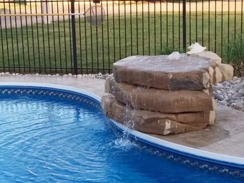 Natural stone waterfall feature cascading into a custom in-ground swimming pool.